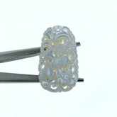 A close-up image of a hand-carved white mother of pearl pendant with a floral and phoenix pattern, attached to a metal clasp.