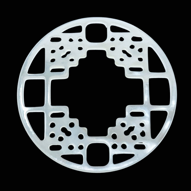 A round white mother of pearl filigree pendant with a carved floral pattern