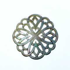 A close-up image of a round black mother of pearl filigree pendant with a metallic sheen, held by a needle.