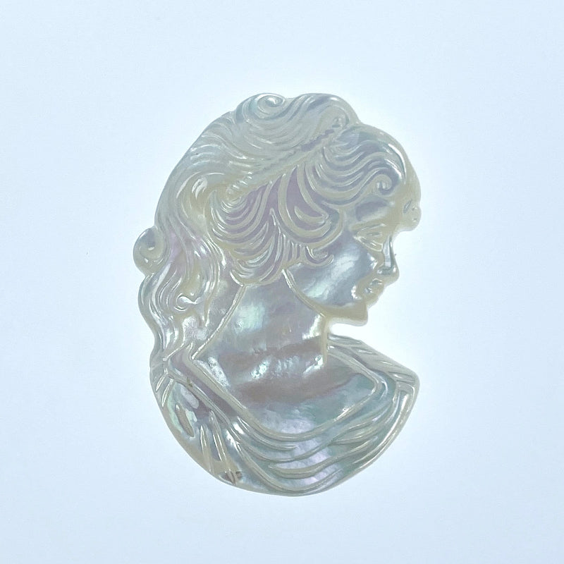 A carved white mother of pearl depicting a Victorian woman's head and neck on a white background.