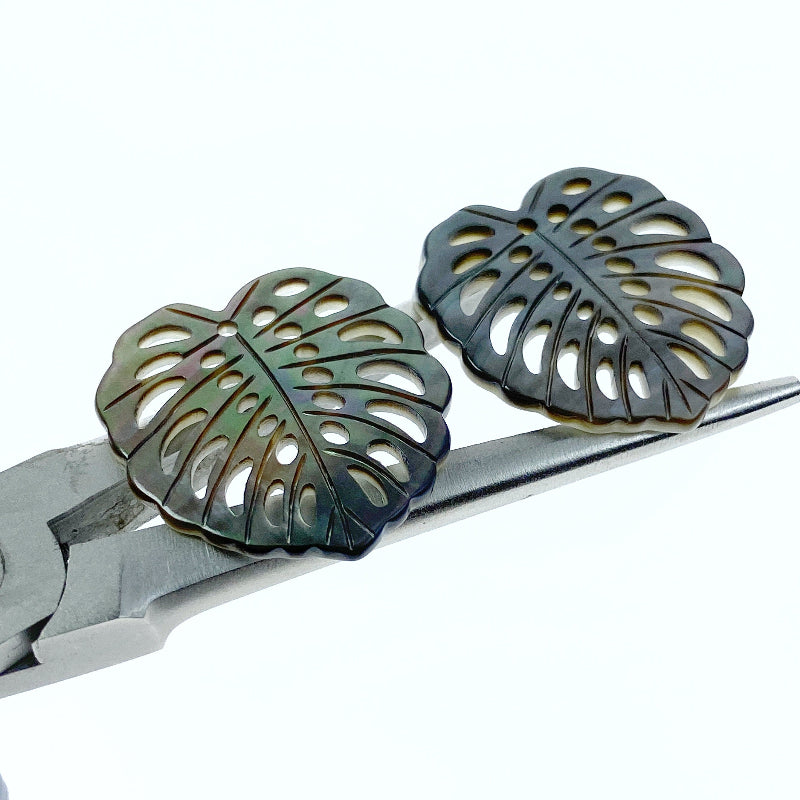 A heart-shaped black mother of pearl bead with a leaf pattern design, with a mix of dark and light brown colors.