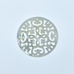 A round white mother of pearl filigree pendant on a white background.