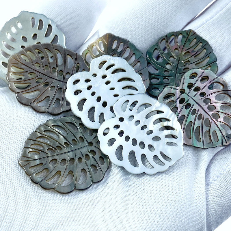 A heart-shaped black mother of pearl bead with a leaf pattern design, with a mix of dark and light brown colors.