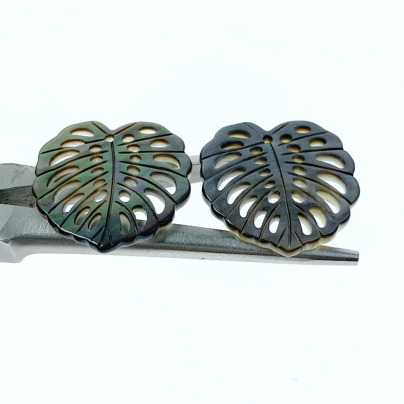 A heart-shaped black mother of pearl bead with a leaf pattern design, with a mix of dark and light brown colors.