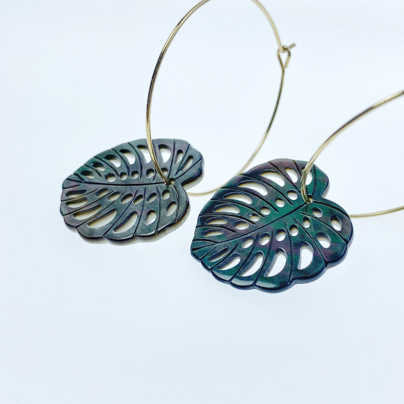 A heart-shaped black mother of pearl bead with a leaf pattern design, with a mix of dark and light brown colors.