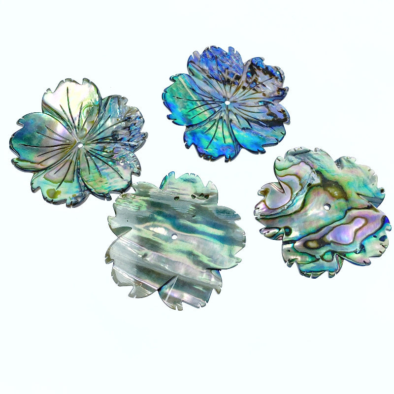 A hand-carved abalone shell flower bead with a natural color pattern resembling a hibiscus flower.